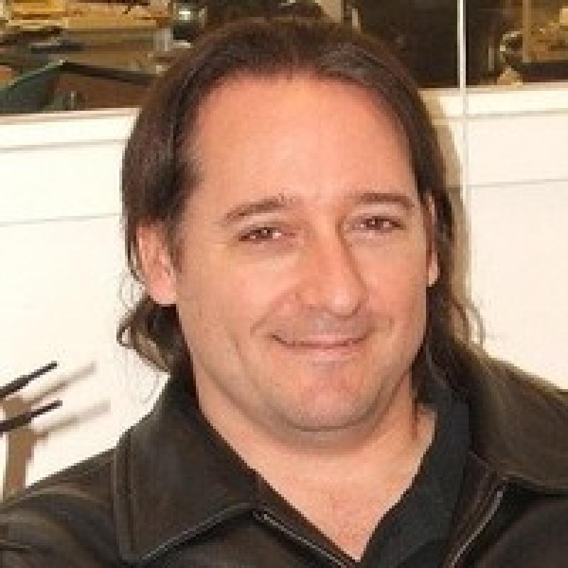 Headshot of a man smiling wearing a black jacket.