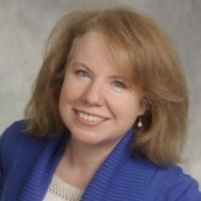 Headshot of a woman smiling wearing a blue blazer.